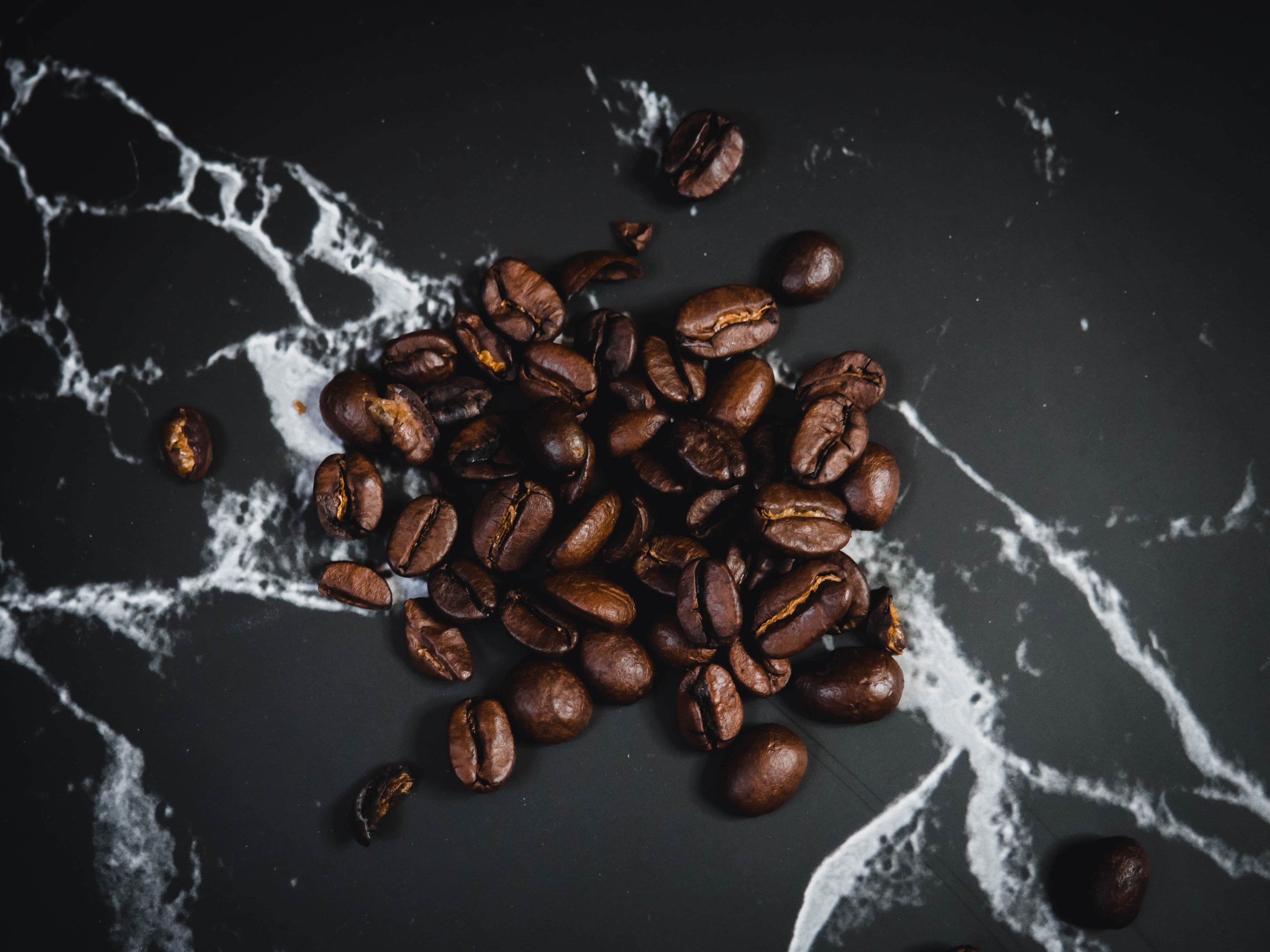 Roasted coffee beans on a black marble surface